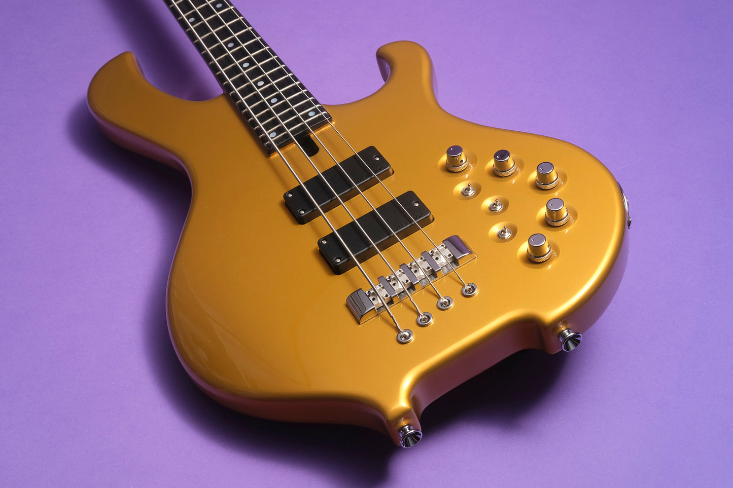 Gold electric bass guitar on a purple background