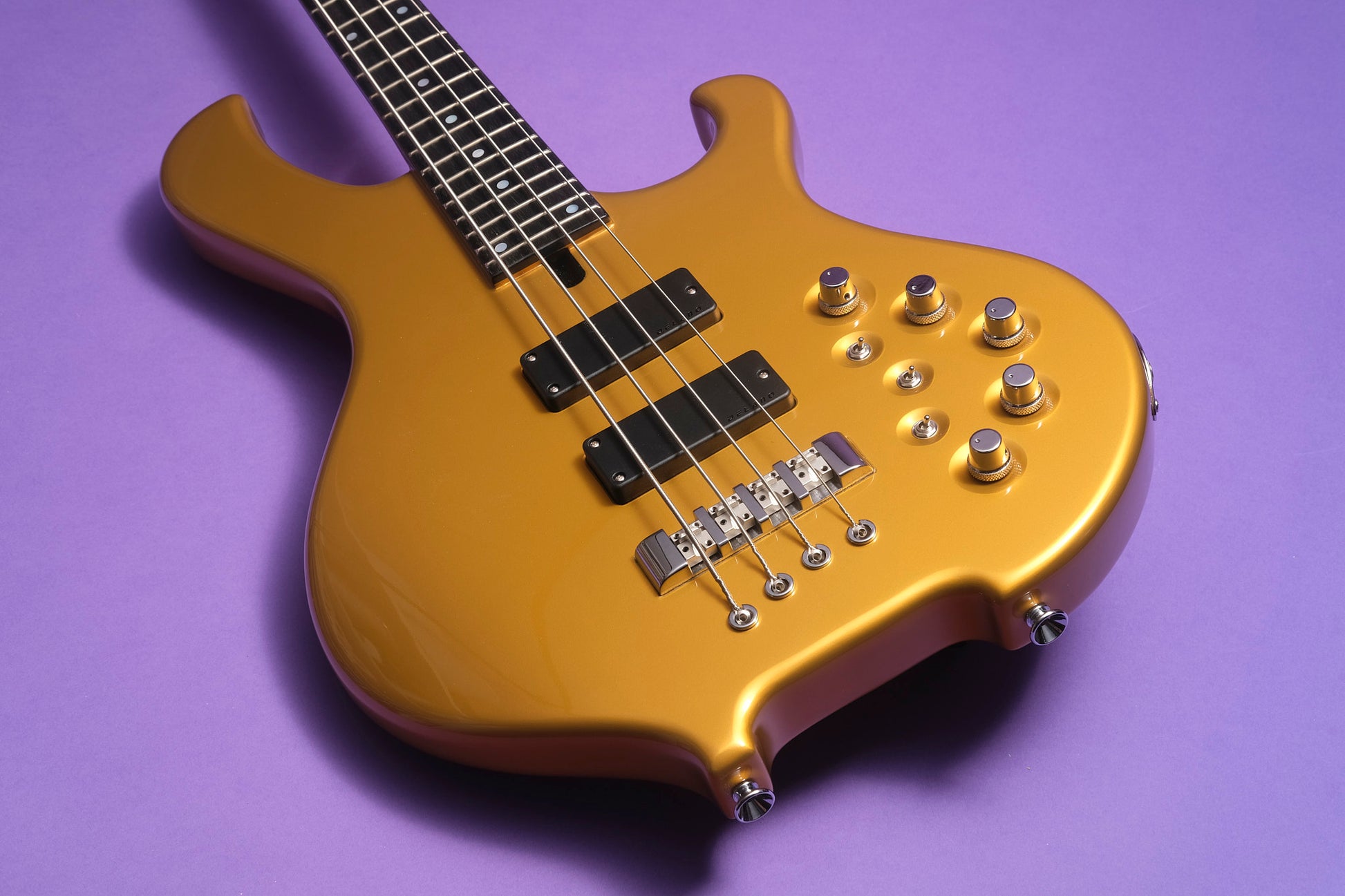 Gold electric bass guitar on a purple background