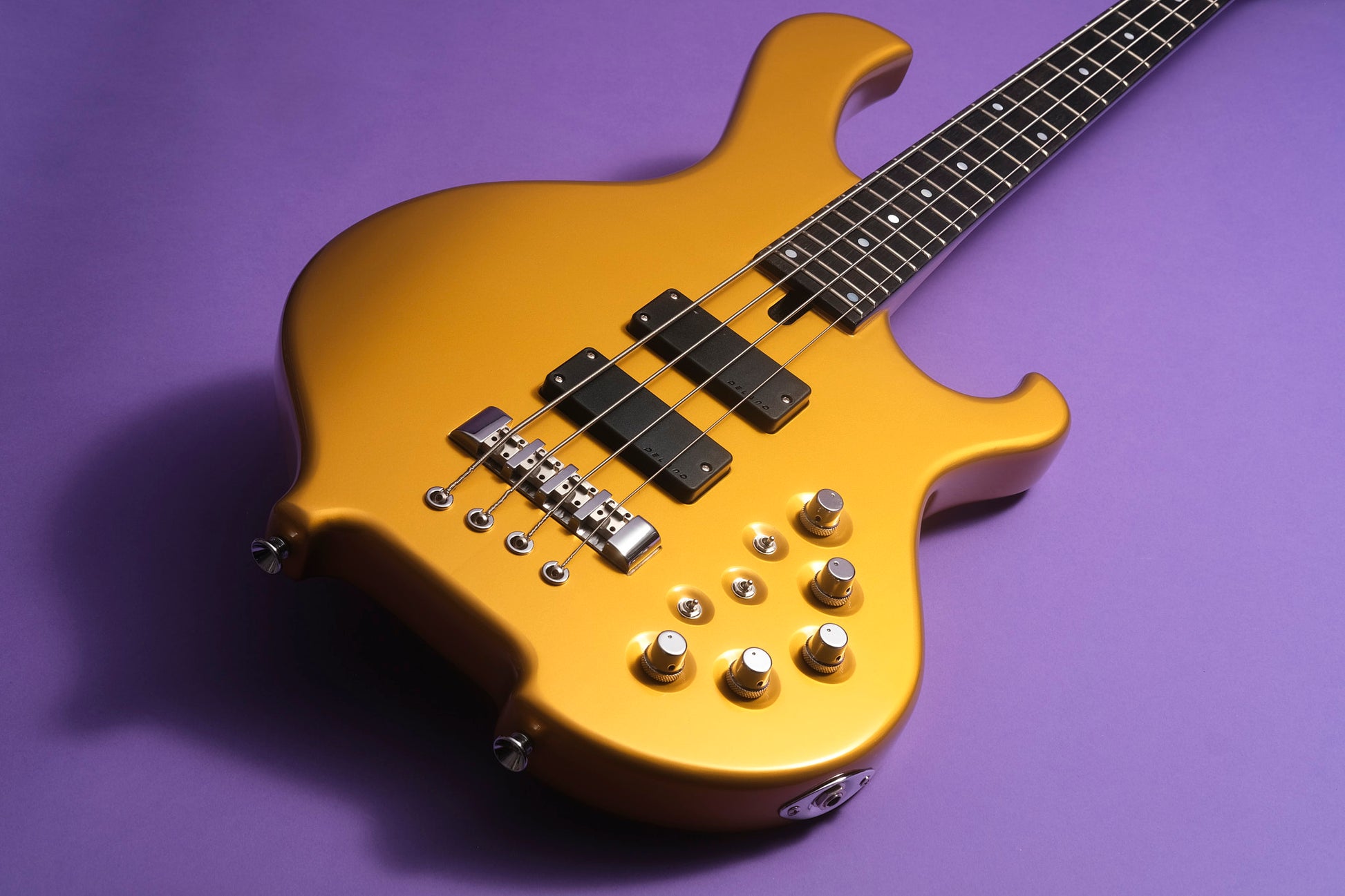 Gold electric bass guitar on a purple background