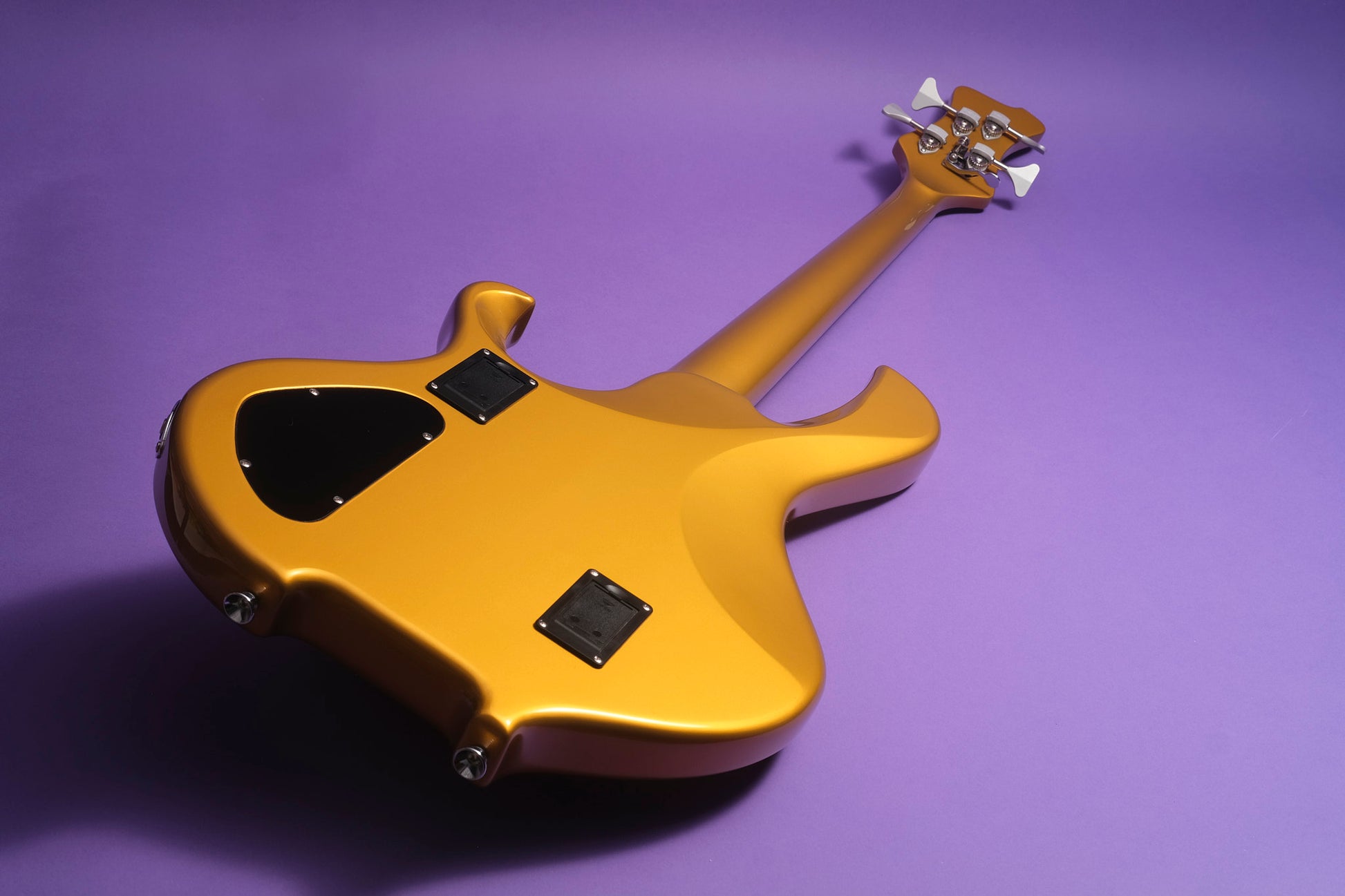 Gold electric bass guitar on a purple background
