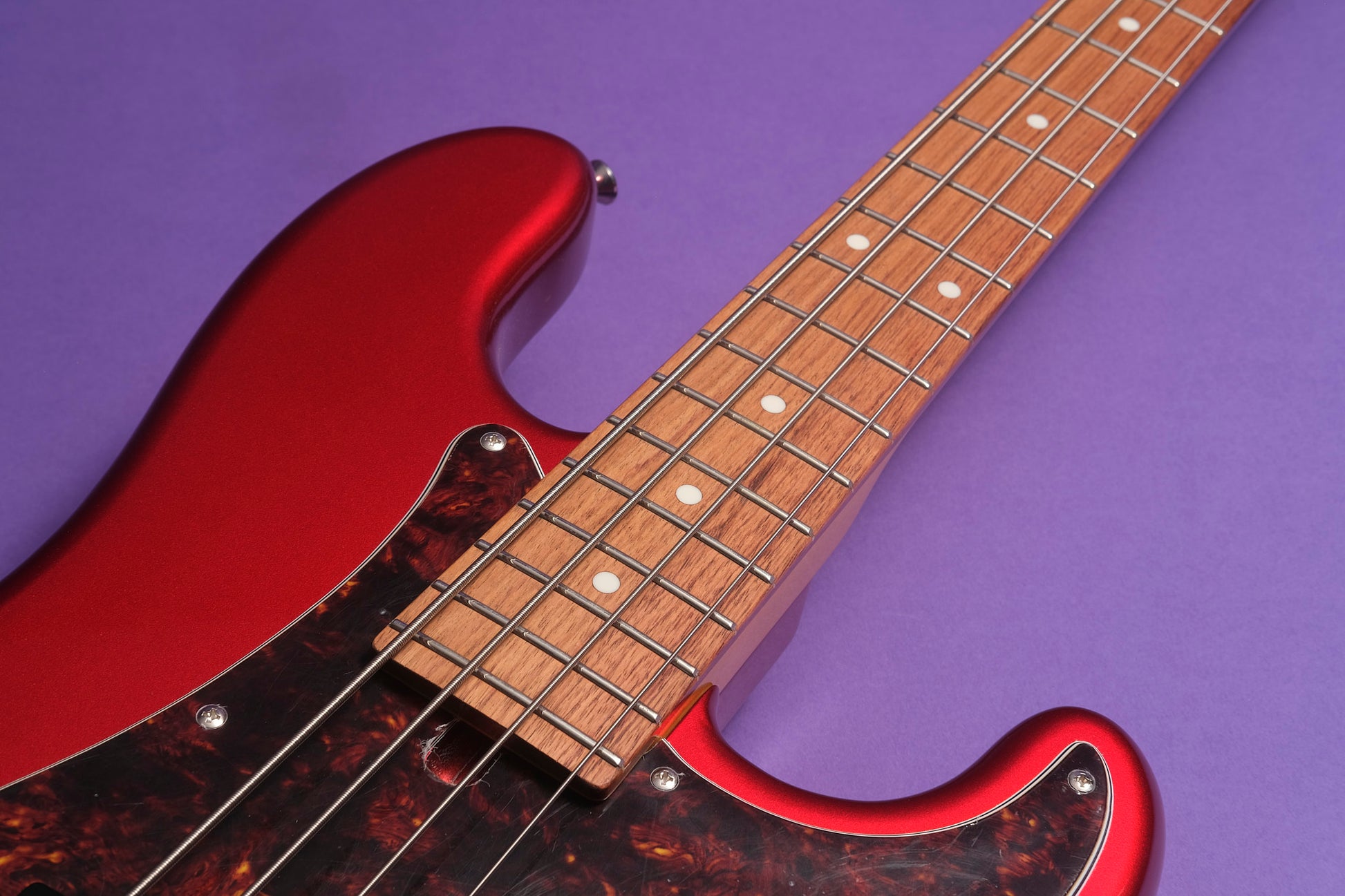 Close-up of a red electric guitar on a purple background
