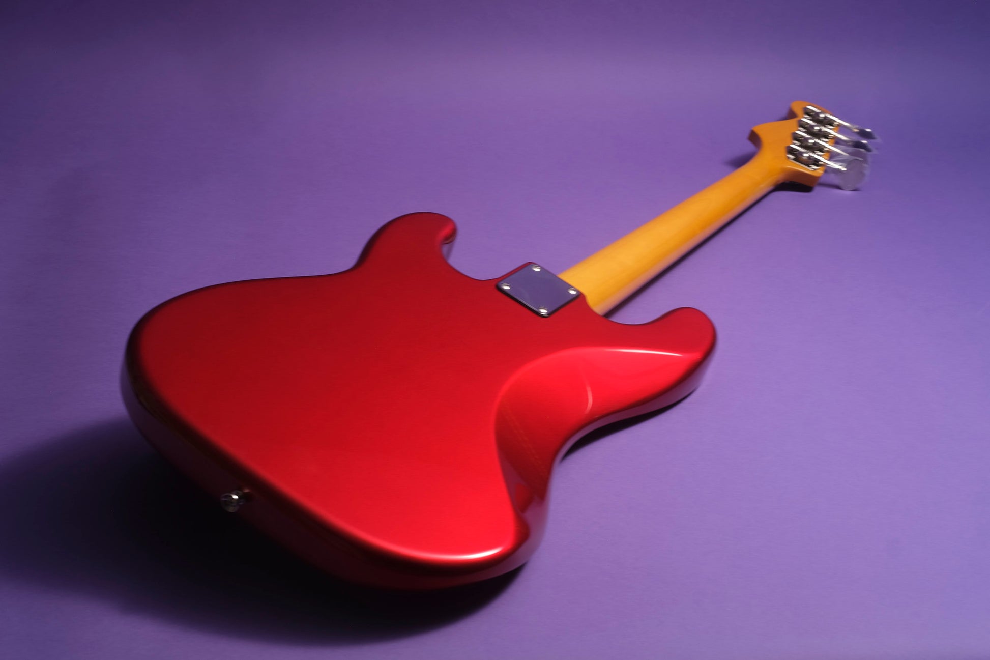 Red electric guitar with a yellow neck on a purple background