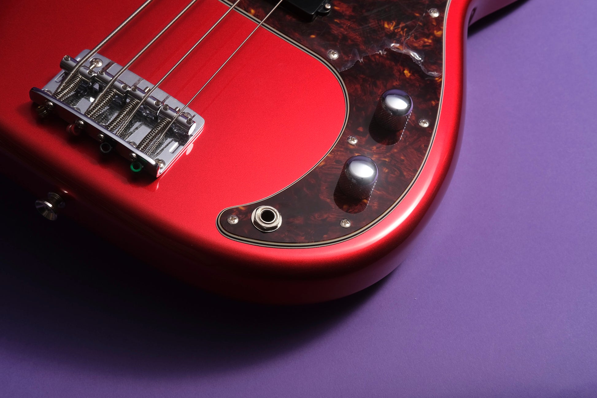 Close-up of a red electric guitar on a purple background